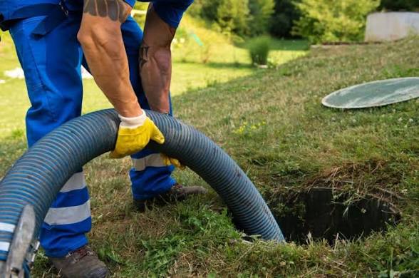 A Joe's Plumbing technician pumping a residential septic tank through an open access lid